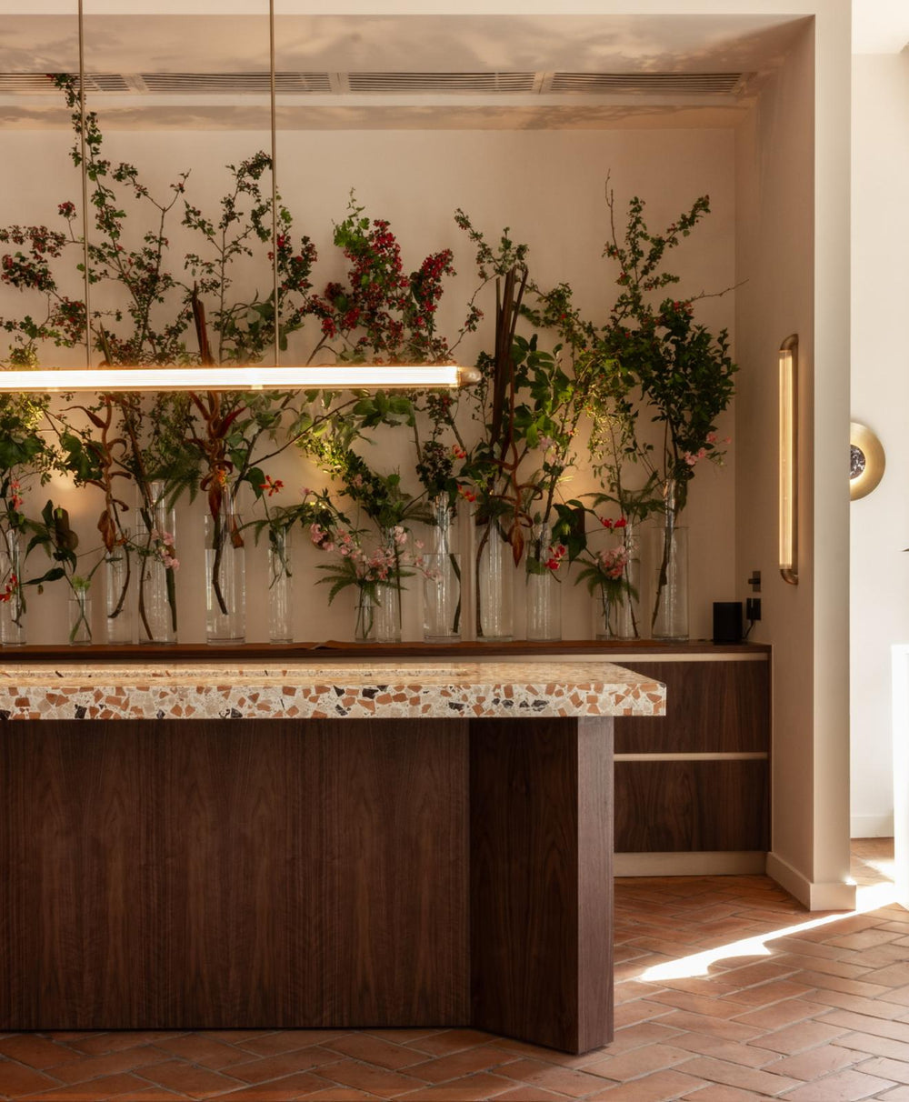 Modern interior with a wooden counter and floral arrangements on a wall.