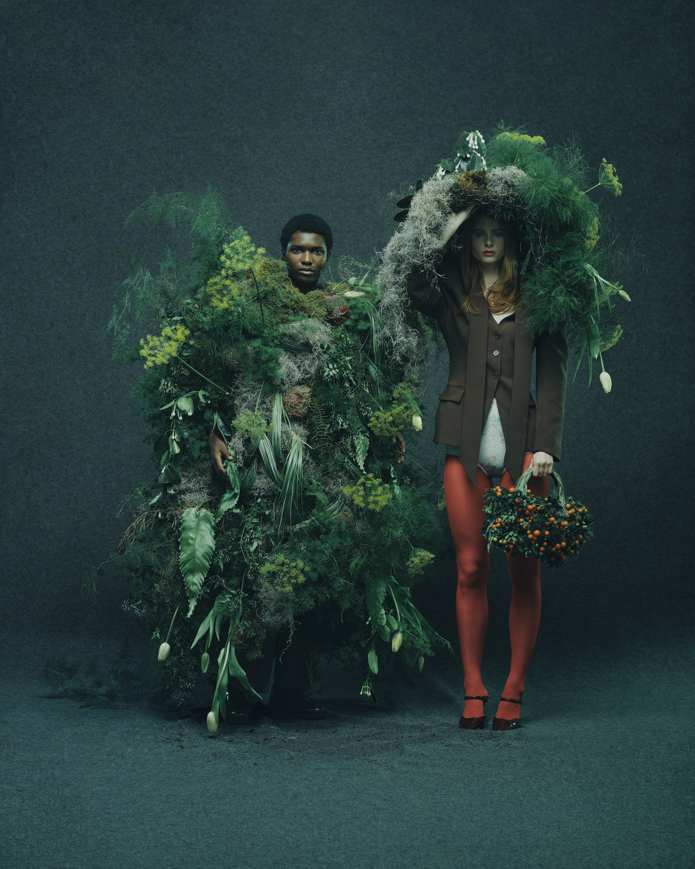 Two floral design models, one with a naturalistic costume and the other holding flowers, set against a dark background.