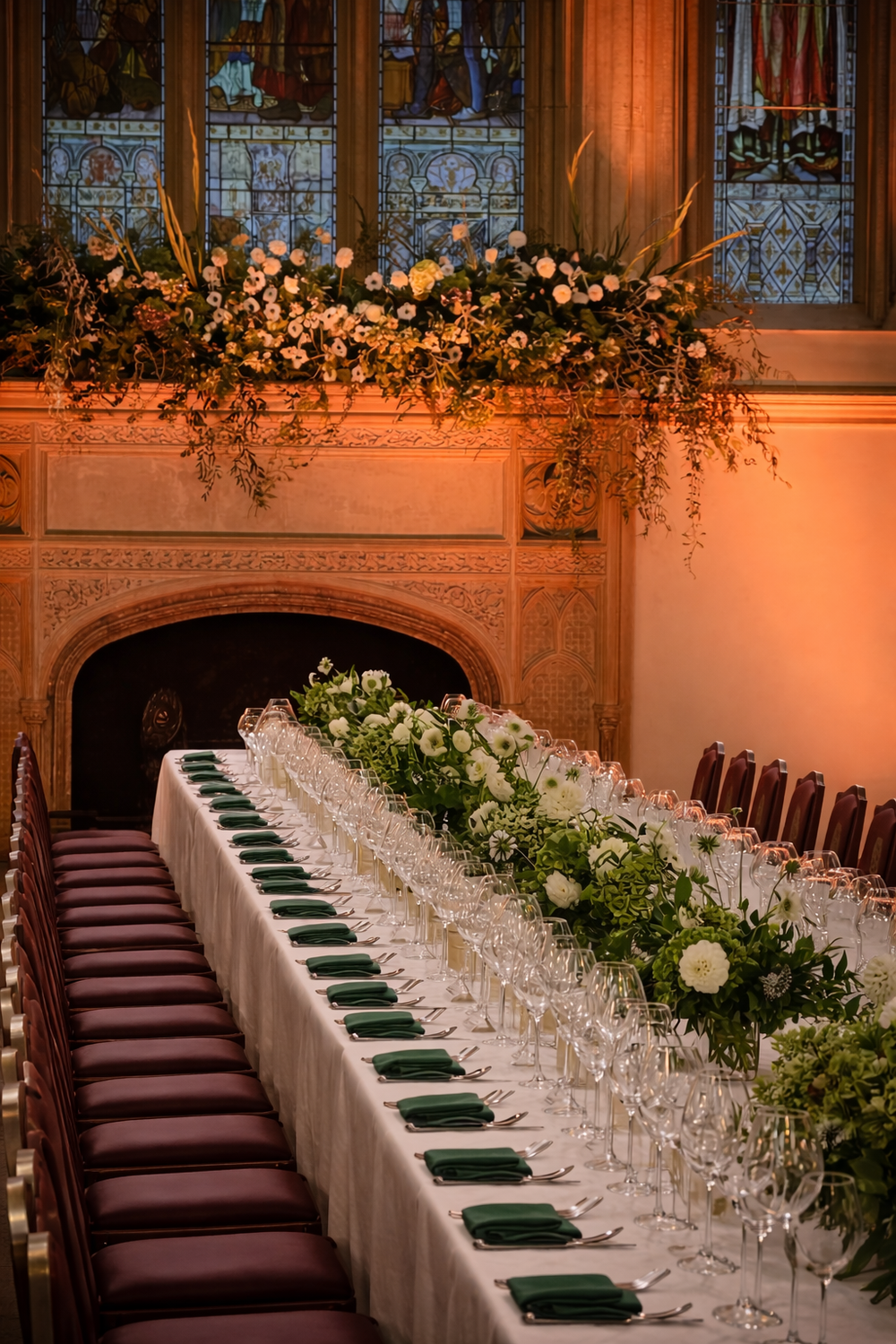 Dining table set for a formal event with floral arrangements and chairs in a grand room.